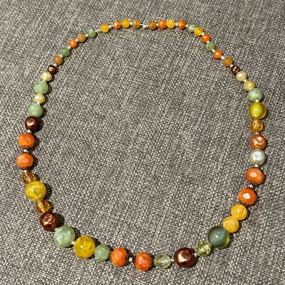 Vintage strung beaded necklace with oranges, greens, yellows, and bronze beads.